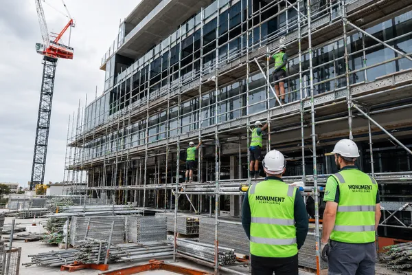 Monument Scaffolding crew reviewing multi-storey scaffold access on a commercial office building construction site